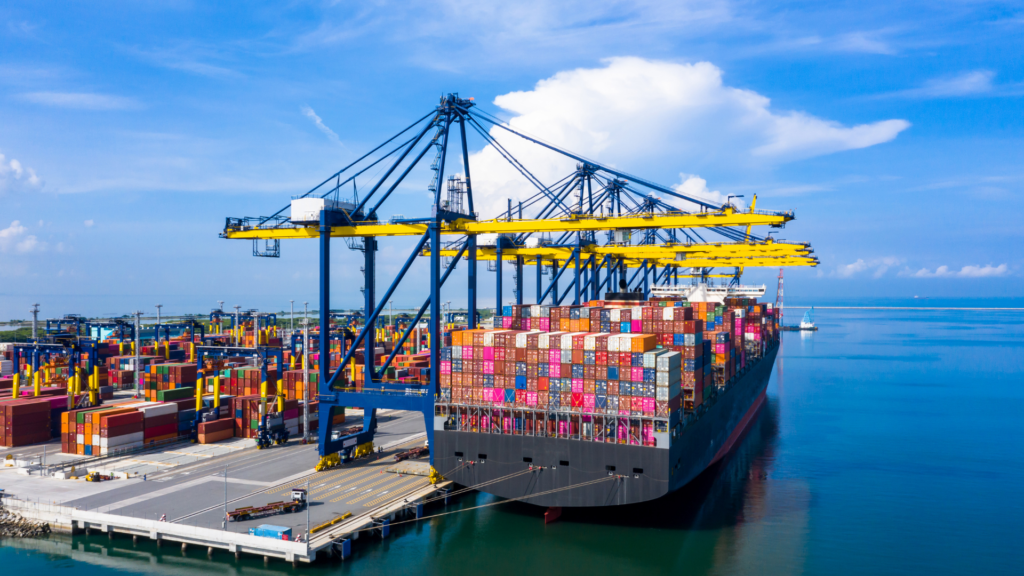 Container de carga sendo descarregado em porto, representando o comércio internacional e importação de produtos.